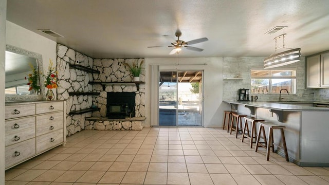 kitchen with tasteful backsplash, a stone fireplace, ceiling fan, and a healthy amount of sunlight