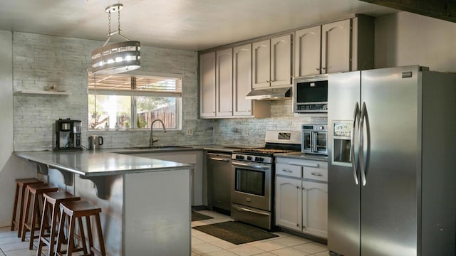 kitchen featuring kitchen peninsula, appliances with stainless steel finishes, sink, light tile patterned floors, and hanging light fixtures