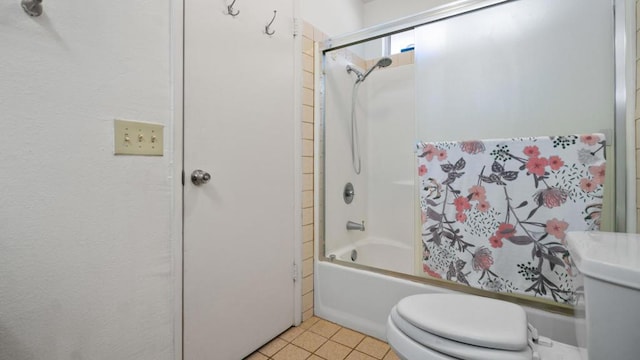 bathroom with tile patterned floors, bath / shower combo with glass door, and toilet