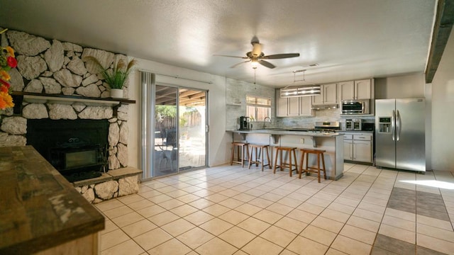 kitchen featuring a breakfast bar, backsplash, ceiling fan, kitchen peninsula, and stainless steel appliances