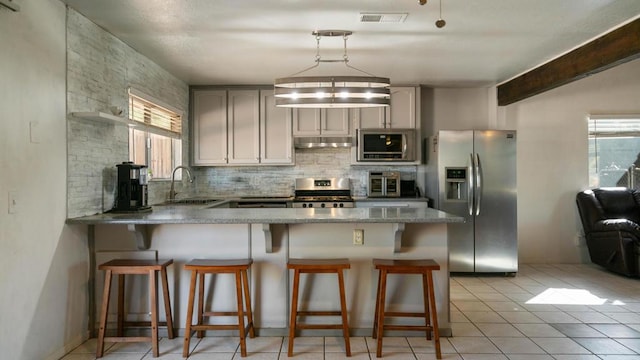 kitchen featuring sink, hanging light fixtures, beamed ceiling, a breakfast bar area, and appliances with stainless steel finishes