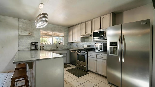 kitchen featuring kitchen peninsula, pendant lighting, a breakfast bar, light tile patterned floors, and appliances with stainless steel finishes