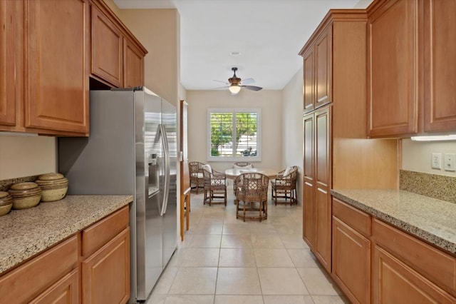 kitchen with light stone countertops, light tile patterned flooring, ceiling fan, lofted ceiling, and stainless steel fridge with ice dispenser