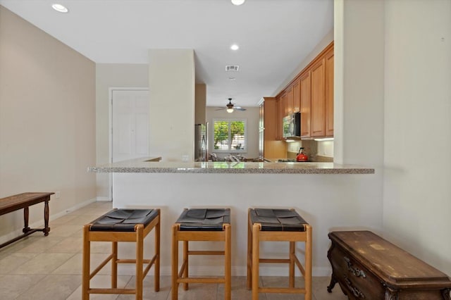 kitchen featuring ceiling fan, light stone countertops, light tile patterned flooring, and kitchen peninsula