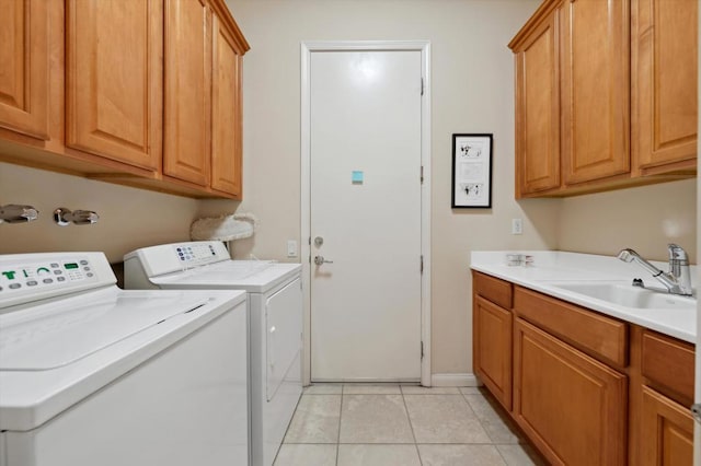 clothes washing area featuring light tile patterned flooring, washing machine and dryer, sink, and cabinets