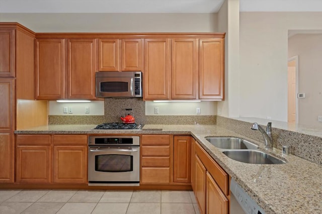 kitchen featuring light stone countertops, sink, appliances with stainless steel finishes, and light tile patterned floors