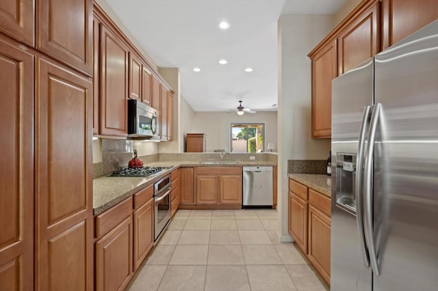 kitchen featuring light tile patterned flooring, backsplash, ceiling fan, stainless steel appliances, and light stone counters