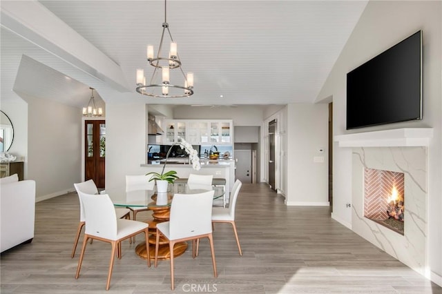 738 Cliff Dr, Laguna Beach, CA 92651 - dining room featuring a chandelier, a fireplace, light wood-type flooring, and baseboards