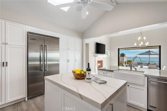 738 Cliff Dr, Laguna Beach, CA 92651 - kitchen with stainless steel appliances, a sink, white cabinetry, light wood finished floors, and a center island