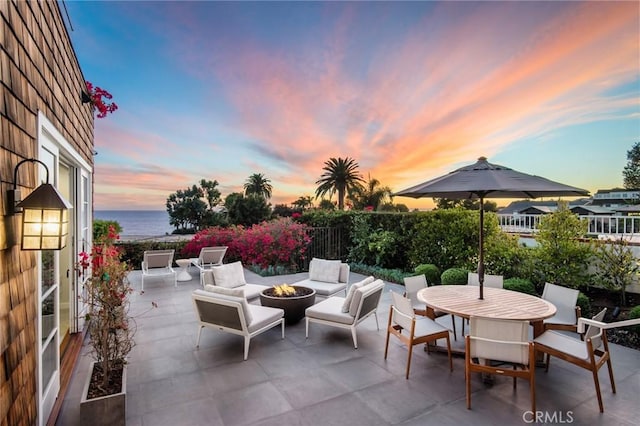 738 Cliff Dr, Laguna Beach, CA 92651 - patio terrace at dusk with an outdoor fire pit, a patio area, outdoor dining space, and a water view