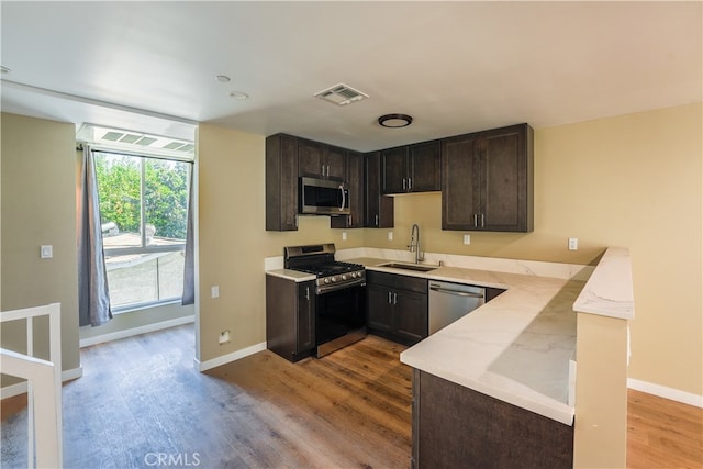 kitchen with sink, dark brown cabinets, stainless steel appliances, and light wood-type flooring