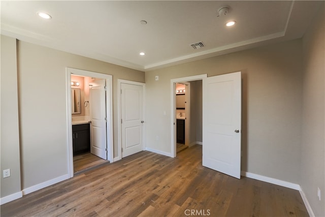 unfurnished bedroom featuring connected bathroom and dark wood-type flooring