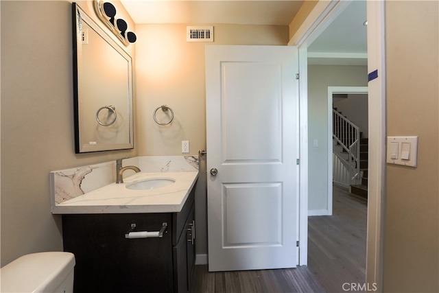 bathroom featuring vanity, wood-type flooring, and toilet