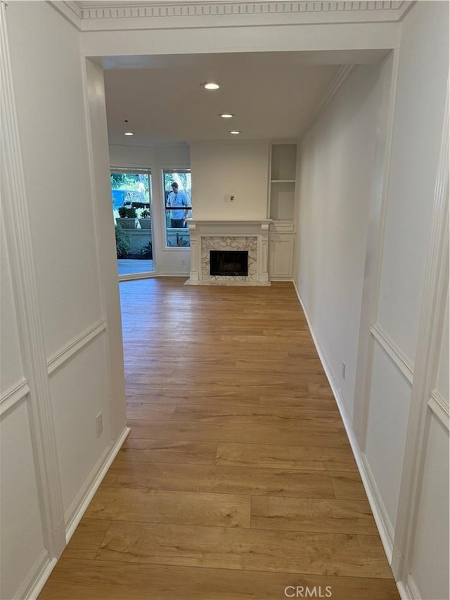 hallway with light hardwood / wood-style floors and crown molding