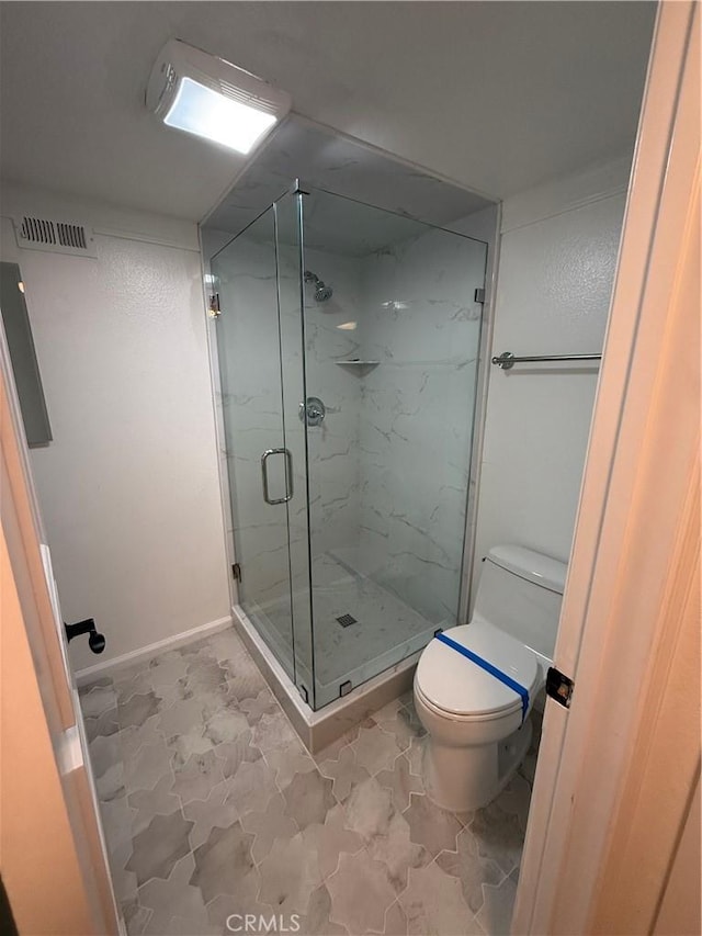 bathroom with tile patterned flooring, toilet, and a shower with door