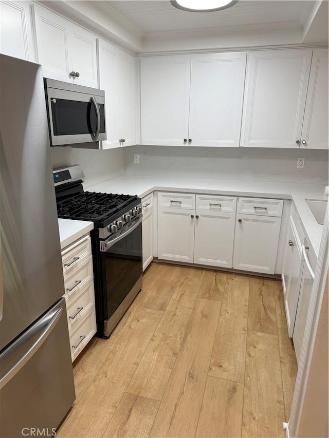 kitchen with light wood-type flooring, white cabinetry, and appliances with stainless steel finishes