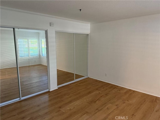 unfurnished bedroom with crown molding and hardwood / wood-style floors