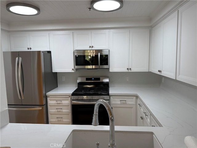 kitchen featuring white cabinetry, sink, light stone counters, and appliances with stainless steel finishes