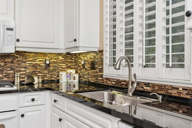 kitchen with white cabinetry, white appliances, backsplash, and a sink