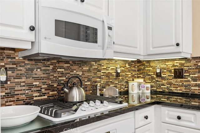 kitchen with white appliances, dark countertops, tasteful backsplash, and white cabinetry