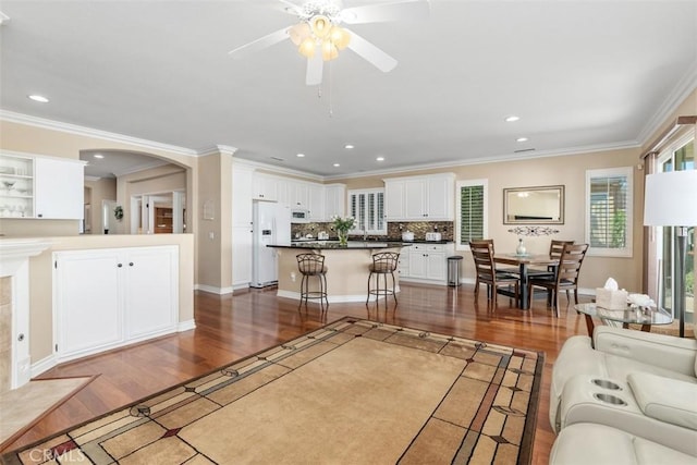 living area featuring recessed lighting, ornamental molding, a ceiling fan, and wood finished floors