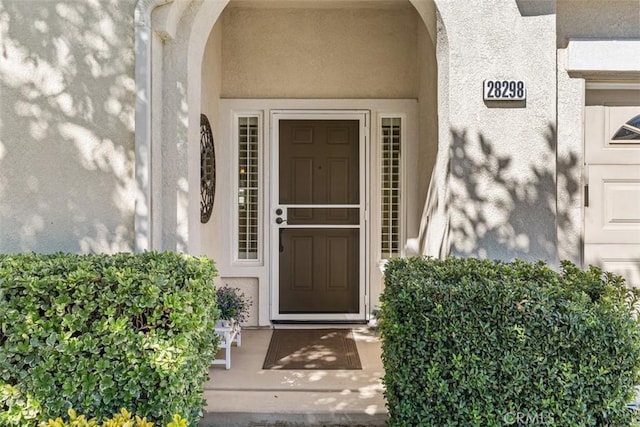 doorway to property featuring stucco siding