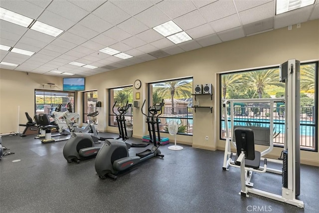 workout area featuring a paneled ceiling and baseboards