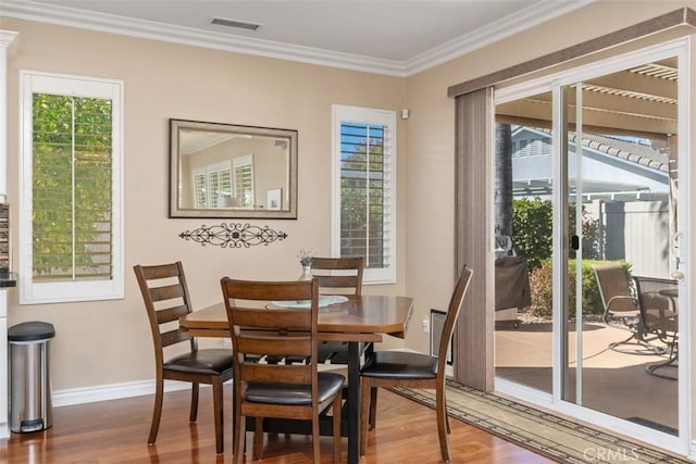 dining space featuring visible vents, ornamental molding, baseboards, and wood finished floors