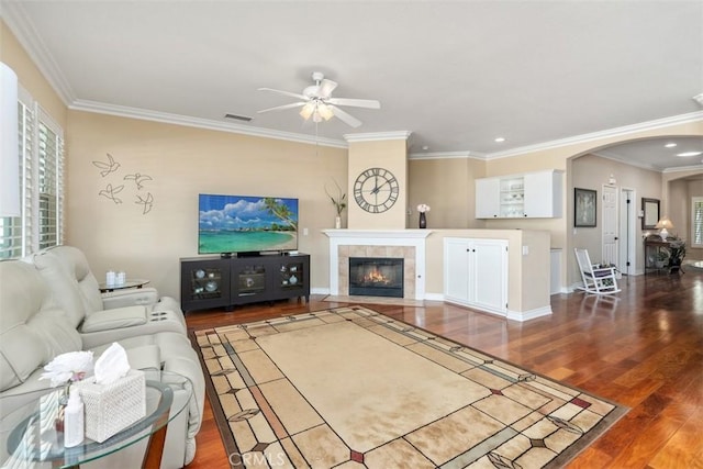 living area featuring a wealth of natural light, visible vents, wood finished floors, arched walkways, and ceiling fan