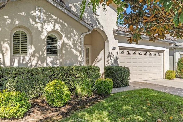 view of front of property with stucco siding, an attached garage, and driveway