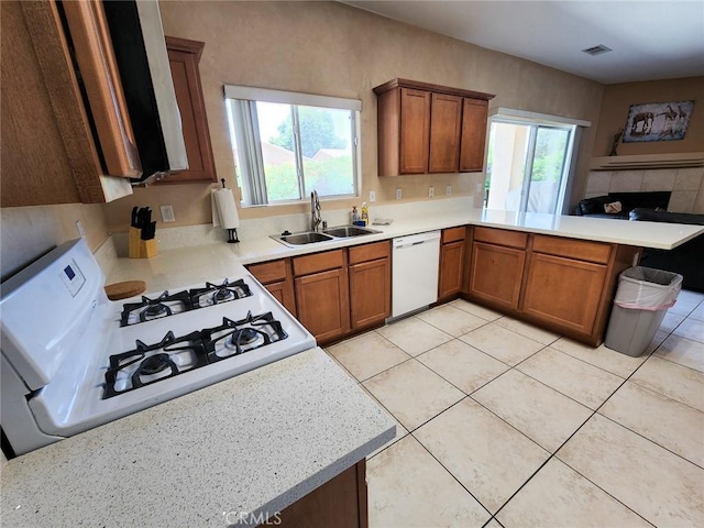 kitchen featuring plenty of natural light, sink, white appliances, and kitchen peninsula