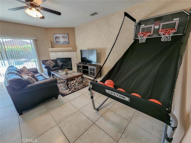 tiled living room featuring ceiling fan and a fireplace