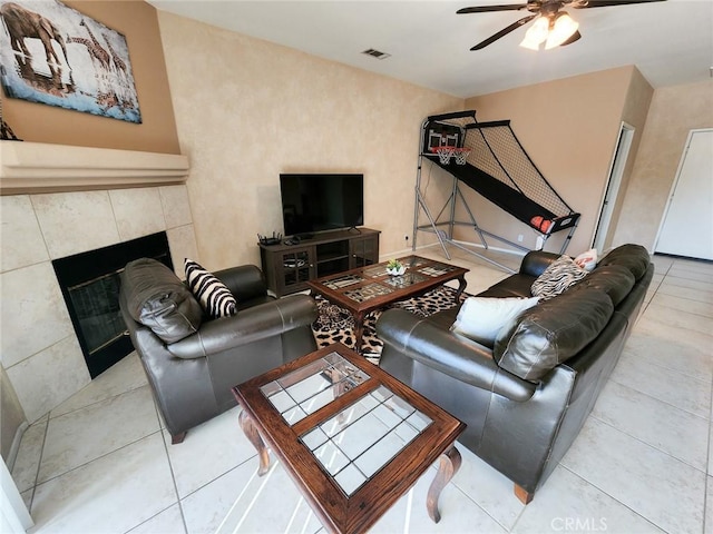 living room with ceiling fan and a tiled fireplace