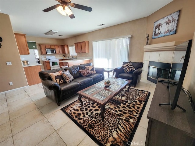 living room featuring sink, a fireplace, ceiling fan, and light tile patterned flooring