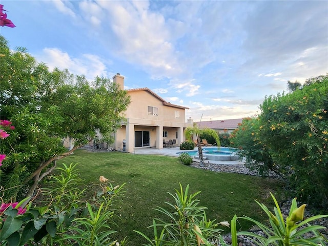 rear view of property with a swimming pool with hot tub, a patio, and a yard