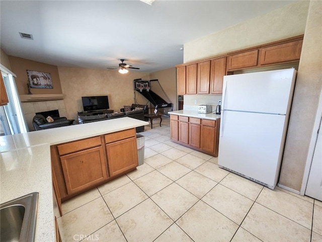 kitchen featuring a tiled fireplace, sink, light tile patterned floors, and white refrigerator