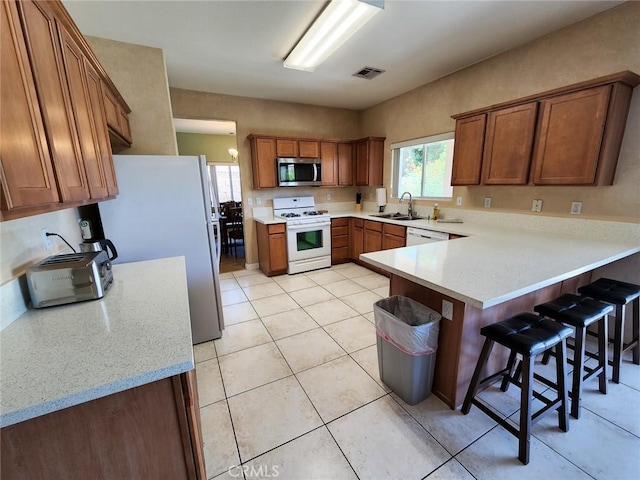 kitchen featuring sink, a kitchen bar, light tile patterned floors, kitchen peninsula, and stainless steel appliances