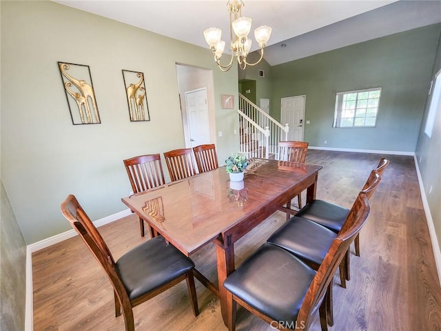 dining area featuring an inviting chandelier, vaulted ceiling, and hardwood / wood-style floors