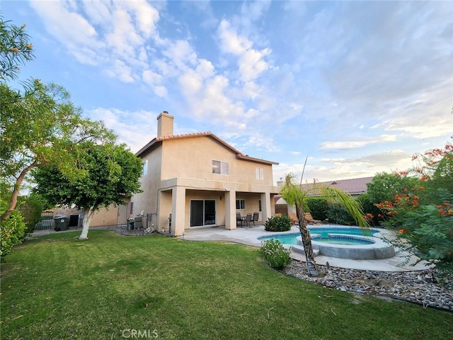 back of property with a swimming pool with hot tub, a lawn, and a patio