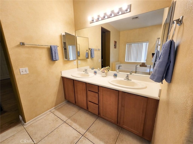 bathroom with tile patterned floors, a bathing tub, and vanity