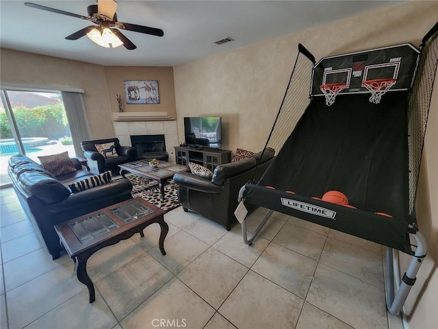 living room with tile patterned flooring, a tile fireplace, and ceiling fan