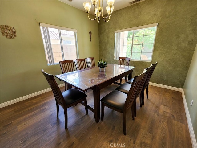 dining area featuring dark wood-type flooring and an inviting chandelier