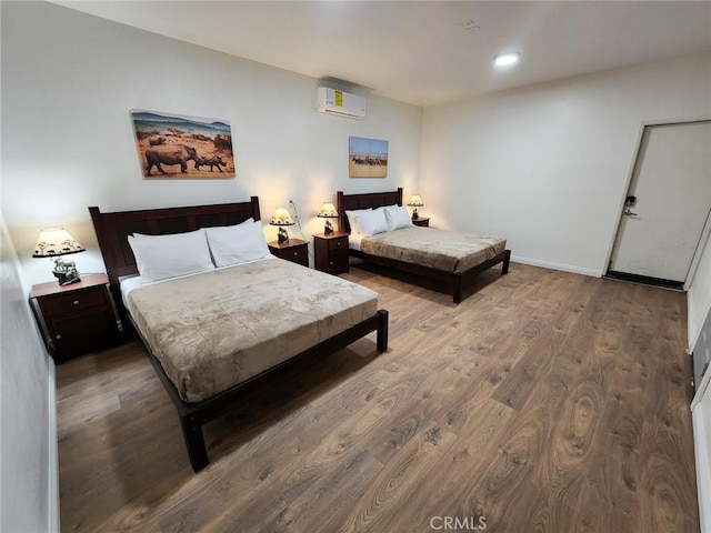 bedroom featuring wood-type flooring and a wall unit AC