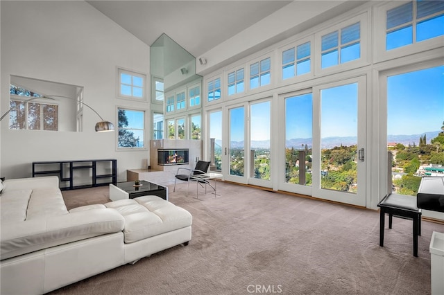 living room with carpet, high vaulted ceiling, and a healthy amount of sunlight