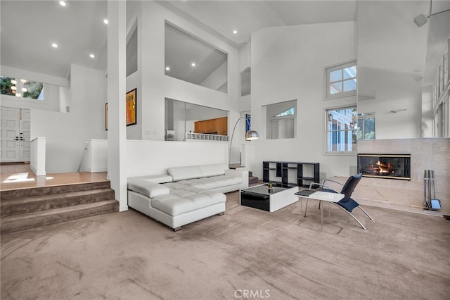 living room with carpet flooring, a tile fireplace, and high vaulted ceiling