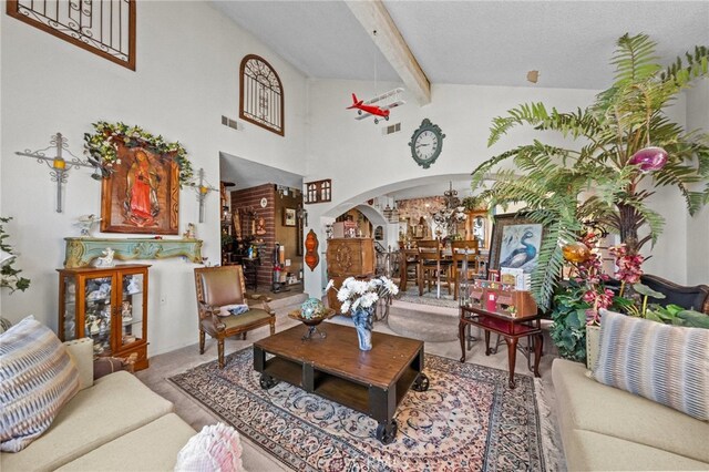 living room with carpet floors, beam ceiling, high vaulted ceiling, and a textured ceiling