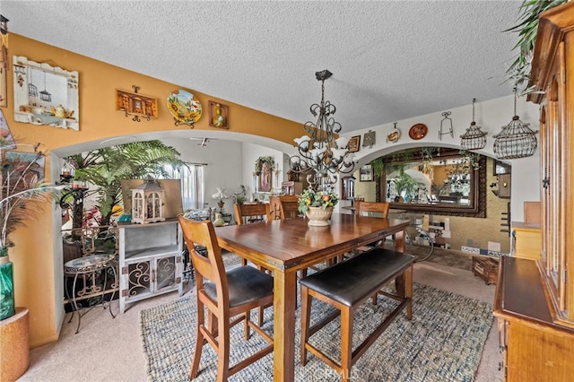 carpeted dining area with a notable chandelier and a textured ceiling