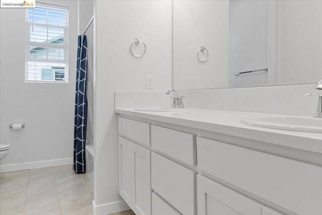 full bathroom featuring tile patterned flooring, shower / bath combo with shower curtain, vanity, and toilet