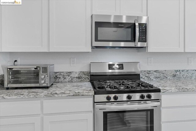 kitchen featuring white cabinetry, light stone countertops, and appliances with stainless steel finishes