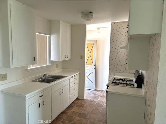 kitchen with white cabinetry, sink, and gas range gas stove